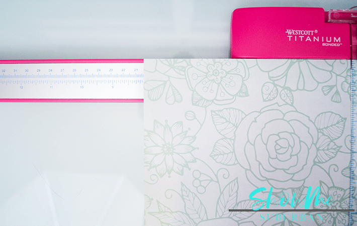Scrapbook paper on paper cutter | Keep your life organized with a cute, custom dry erase board! This easy DIY project is perfect for chore lists, weekly menu, family command centers, to-do lists, reminders, and more! #organized