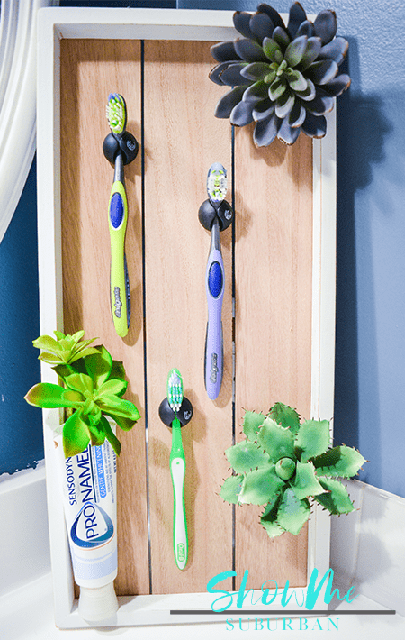 DIY toothbrush holder with toothbrushes and faux succulents | Spruce up your bathroom with this cute DIY toothbrush storage unit! This toothbrush holder helps toothbrushes dry and reduces messes. Try this quick and easy idea today. Also makes a great gift! #diydecor #organizedbathroom